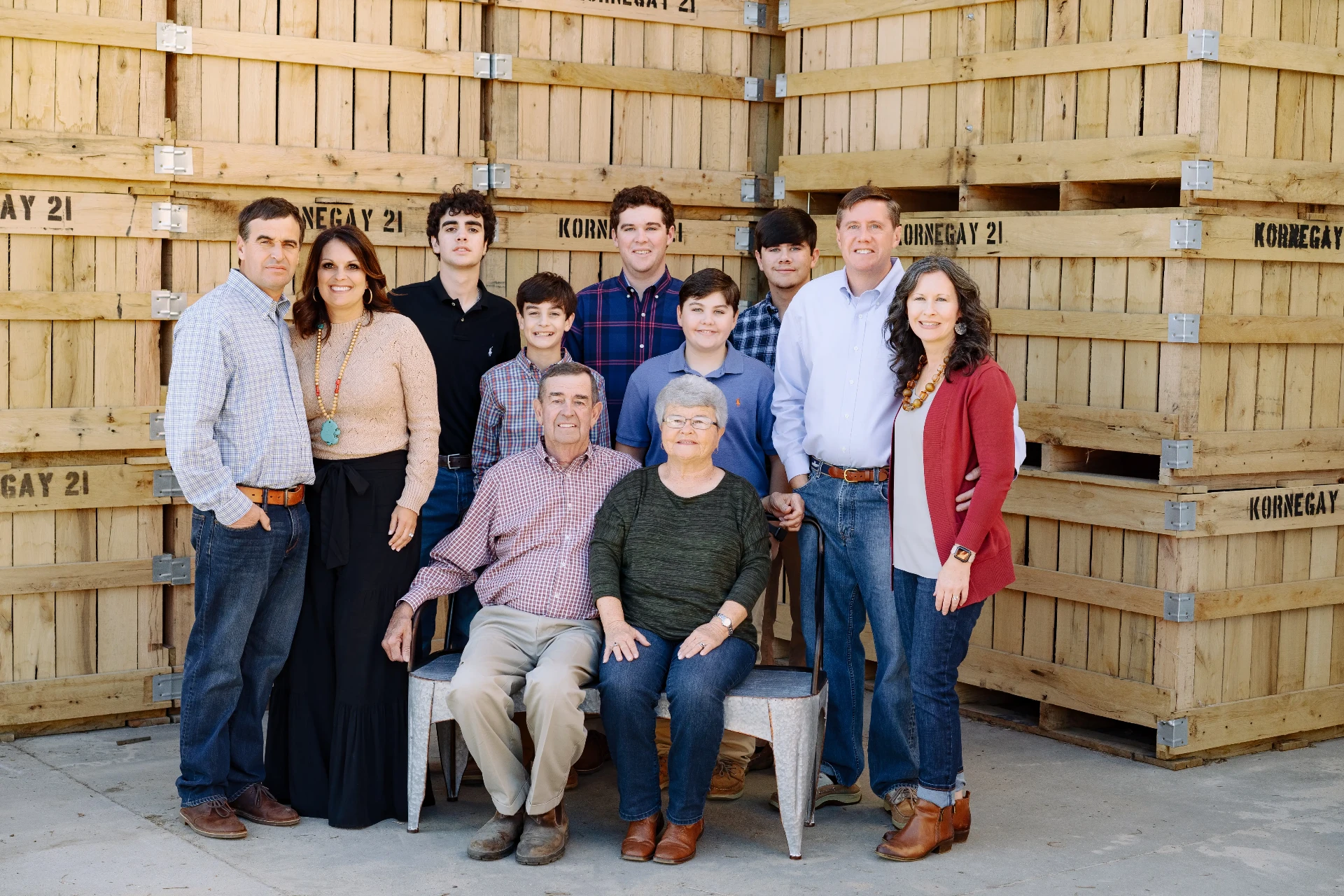 Three generations of the Kornegay family photographed in front of stacked wooden sweetpotato crates stamped Kornegay 21.